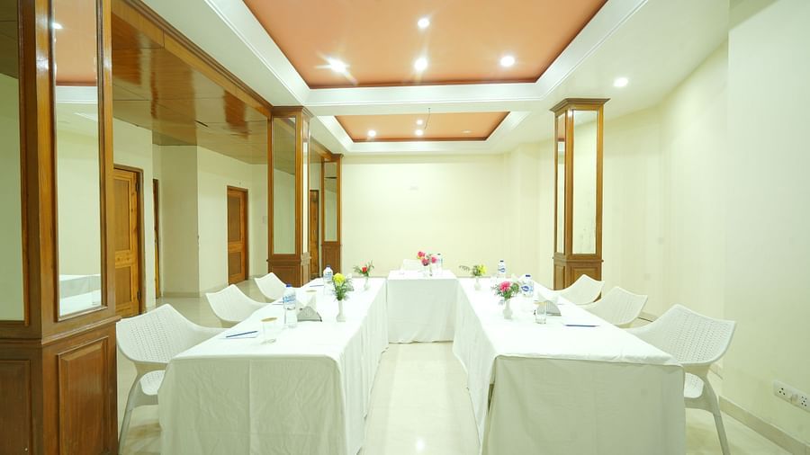 Conference hall with chairs and tables arranged under white lighting at DLS Hotels The Rock Castle.